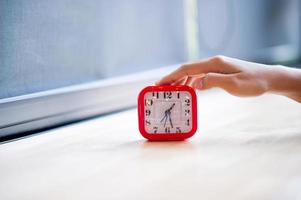 main et réveil rouge qui montre l'alarme du tout tous les matins, le concept de ponctualité photo