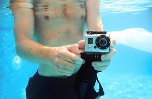 jeune homme prenant des photos sous l'eau dans la piscine en été