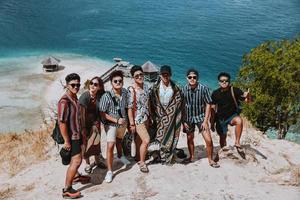 les touristes asiatiques prennent une photo ensemble sur les collines avec une plage exotique à labuan bajo