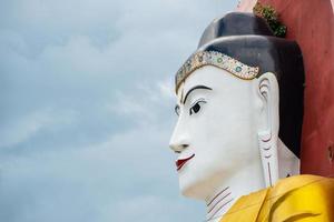 l'une des quatre grandes images de bouddha assises dos à dos dans la pagode kyaik pun, l'un des lieux d'attraction touristique de la ville de bago, au myanmar. photo