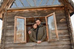 couple amoureux regarde par la fenêtre, maison en bois. le concept d'achat de nouveaux logements pour les jeunes familles. photo