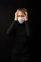 un homme d'âge moyen avec un portrait de masque médical en gros plan illustre une pandémie de coronavirus sur fond sombre. concept de contamination de l'épidémie de covid-19. photo