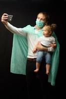 père dans un masque médical tient sa petite fille. le concept de protection des enfants pendant l'épidémie de coronavirus photo