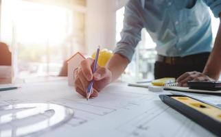 mains d'architecte ou d'ingénieur à l'aide d'une boussole de dessin avec plan sur le bureau au bureau.équipe d'ingénieurs architectes discutant et vérifiant les documents et le flux de travail d'entreprise.concept de construction. photo