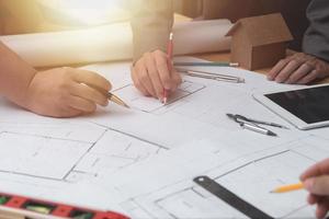 équipe d'architectes ou d'ingénieurs discutant sur le bureau avec un plan sur le nouveau projet de démarrage sur le bureau. groupe d'équipe sur le site de construction vérifier les documents et le flux de travail d'entreprise. mise au point sélective. photo