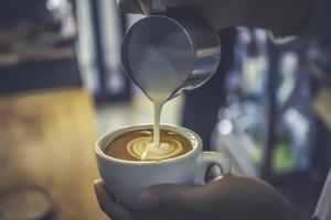 le barista fait du latte art en dessinant sur une tasse de café. photo
