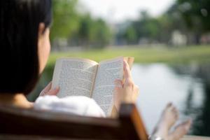 belle jeune femme lisant un livre sur une chaise longue au bord de la piscine photo