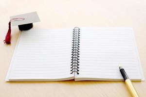 cahier vierge sur la table et chapeau de graduation photo