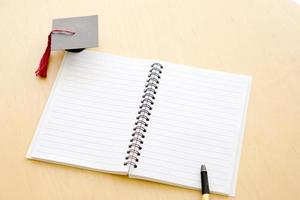 cahier vierge sur la table et chapeau de graduation photo