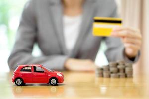 main de femme d'affaires tenir une carte de crédit, une petite voiture et une pile de pièces photo