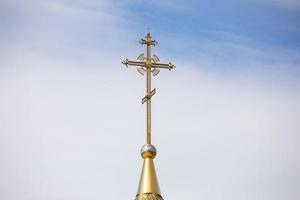 le dôme doré et la croix de l'église orthodoxe contre le ciel bleu et les nuages. photo