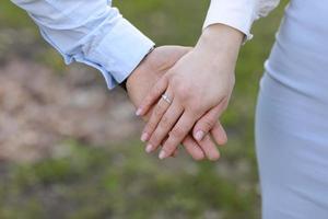 couple amoureux se tient la main dans un champ vert en été. gros plan photo