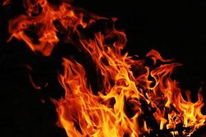 le feu crée des formes infinies lorsqu'il brûle. l'orange de la flamme et le fond noir créent des textures intéressantes. flammes de l'enfer. puissance brûlante. photo
