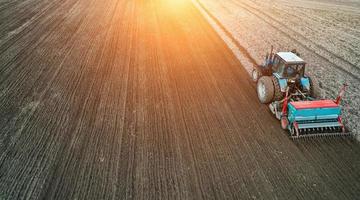 vue aérienne du tracteur sur le terrain, travail sur le terrain agricole, travail de semis sur le terrain au coucher du soleil photo