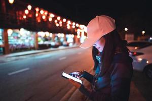 elle utilise un smartphone pour le transport en taxi dans la rue commerçante de nuit. photo