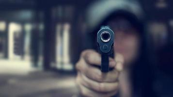 femme pointant un pistolet sur la cible sur fond sombre, mise au point sélective sur le pistolet avant, ton de couleur vintage photo