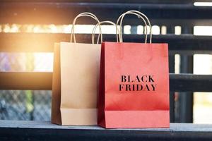 mot du vendredi noir sur des sacs à provisions en papier rouge et brun placés dans les escaliers à l'extérieur sur le fond du centre commercial, concept de commerce de détail.