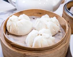 délicieux dim sum, célèbre cuisine cantonaise en asie - cha siu bao frais et chaud, pain de porc barbecue dans un bateau à vapeur en bambou au restaurant yumcha de hong kong, gros plan photo