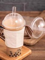 plats à emporter avec concept d'article jetable populaire taïwan boire du thé au lait à bulles avec une tasse en plastique et de la paille sur fond de table en bois, gros plan, espace de copie photo