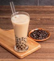 boisson populaire de taiwan - thé au lait à bulles avec boule de perle de tapioca dans un verre à boire et de la paille, table en bois fond de brique grise, gros plan, espace de copie photo