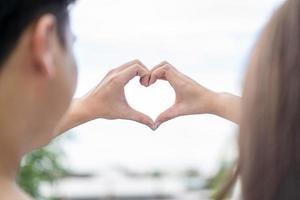 le marié et la mariée coordonnent leur main pour créer une forme de coeur avec le ciel clair photo