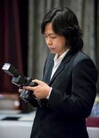 photographe asiatique aux cheveux longs en costume bleu marine concentré avec son appareil photo. photo