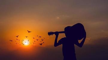 la silhouette d'un guitariste qui tient une guitare et a un coucher de soleil, concept de silhouette. photo