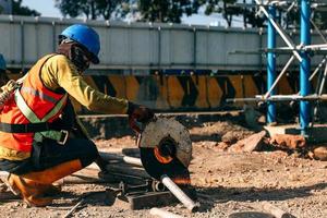 un ouvrier du bâtiment dans un équipement de protection de sécurité travaillant avec un broyeur de fer. bandung, indonésie-17 mars 2022 photo