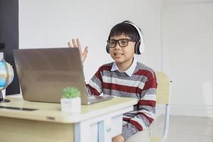 étudiant asiatique souriant faisant un appel vidéo et saluant l'ordinateur portable photo