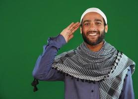 garçon musulman indien saluant sur fond d'écran vert. photo