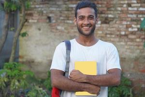 un homme debout dans le jardin avec un sac de transport et un livre photo