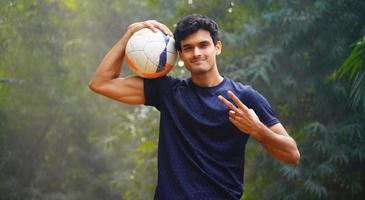 jeune joueur de football montrant le signe de la victoire sur le terrain de football image de l'homme indien photo