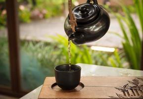 versez à la main du thé traditionnel chinois ou japonais à partir d'un pot en argile photo