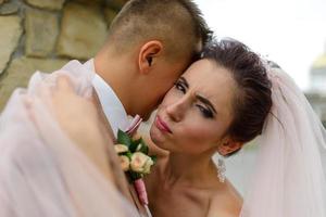 la mariée et le marié s'étreignent sous un voile et s'inclinent doucement la tête l'un vers l'autre. photo