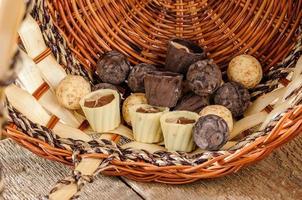 chocolats et chocolat dans un panier sur une table en bois photo