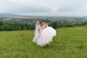 la mariée et le marié s'étreignent sous un voile et s'inclinent doucement la tête l'un vers l'autre. photo