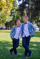deux petits garçons, les frères sont vêtus d'un costume. les enfants sont debout dans le parc et s'embrassent. photo