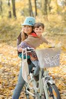 maman et fille s'amusent sur le même vélo. séance photo d'automne.