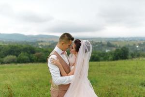 la mariée et le marié s'étreignent sous un voile et s'inclinent doucement la tête l'un vers l'autre. photo