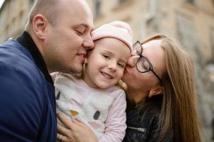 les parents et leur fille sont assis sur les marches d'une vieille église. photo