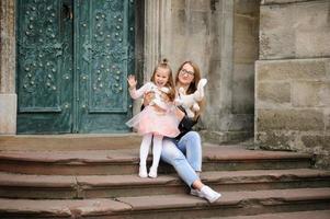 les parents et leur fille sont assis sur les marches d'une vieille église. photo