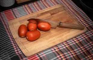 tomate à bord avec un couteau bien aiguisé photo