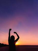 silhouette de jeune femme au lever du soleil sur fond de mer. photo