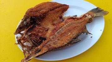 délicieux poisson asiatique frit servi sur une table jaune. cuisine thaïlandaise photo