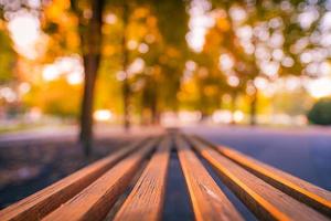 banc en bois rural agrandi. fond de paysage doré d'automne. relaxant, lumière du soleil sereine, rayons du coucher du soleil, paysage du parc naturel photo