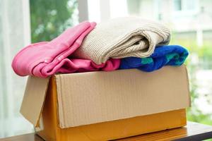 dons de vêtements dans une boîte en carton pour les bénévoles. photo