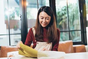 PME petite entreprise asiatique femme entrepreneur ou propriétaire de magasin mettant du tissu dans des emballages en papier pour emballer la commande du client en préparant avant l'expédition de la livraison. heureux succès vendeur femme. photo