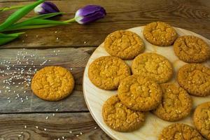 biscuits au sésame faits maison et deux tulipes violettes sur fond rustique photo