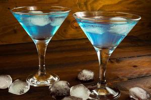 Deux cocktails bleus dans des verres sur fond de bois foncé photo