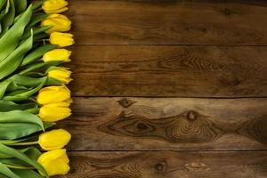 Bouquet de tulipes jaunes sur fond de bois photo